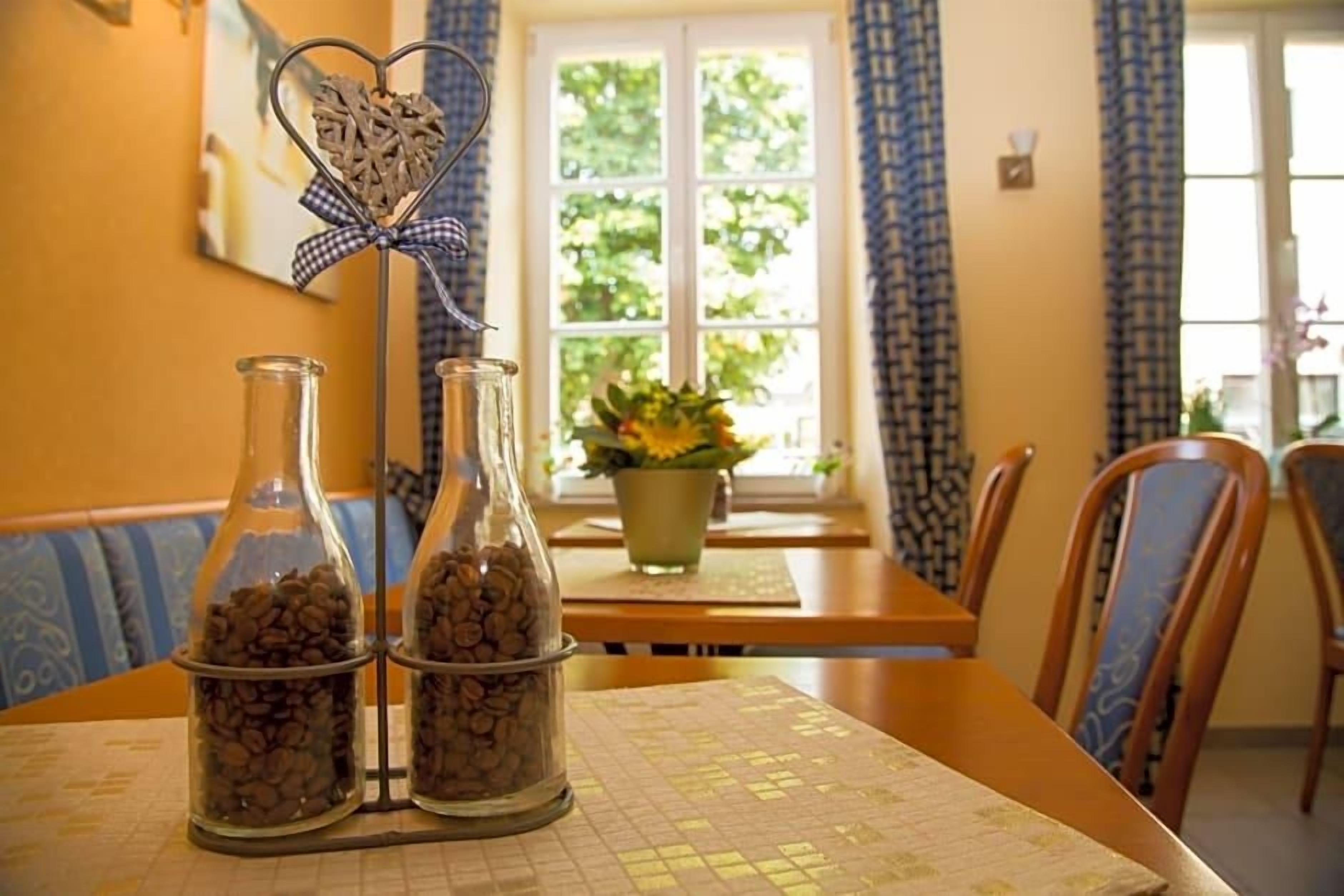 Comedor con una mesa dispuesta para dos personas, con mantel estampado y una ventana con cortinas.
