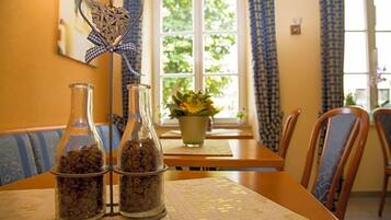 Comedor con una mesa dispuesta para dos personas, con mantel estampado y una ventana con cortinas.