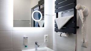 A bathroom with a sink, mirror, towel rack, and hairdryer.