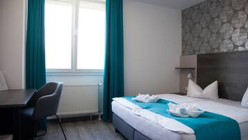 A hotel room with a bed, a desk, and a chair.