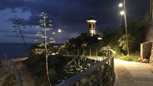 A coastal walkway with a lighthouse, palm trees, and a view of the sea. - Wonderful secluded place - il wokini (Pigna)