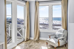 Enjoy a serene view of the snowy landscape from this cozy corner room, featuring a comfortable armchair and large windows.