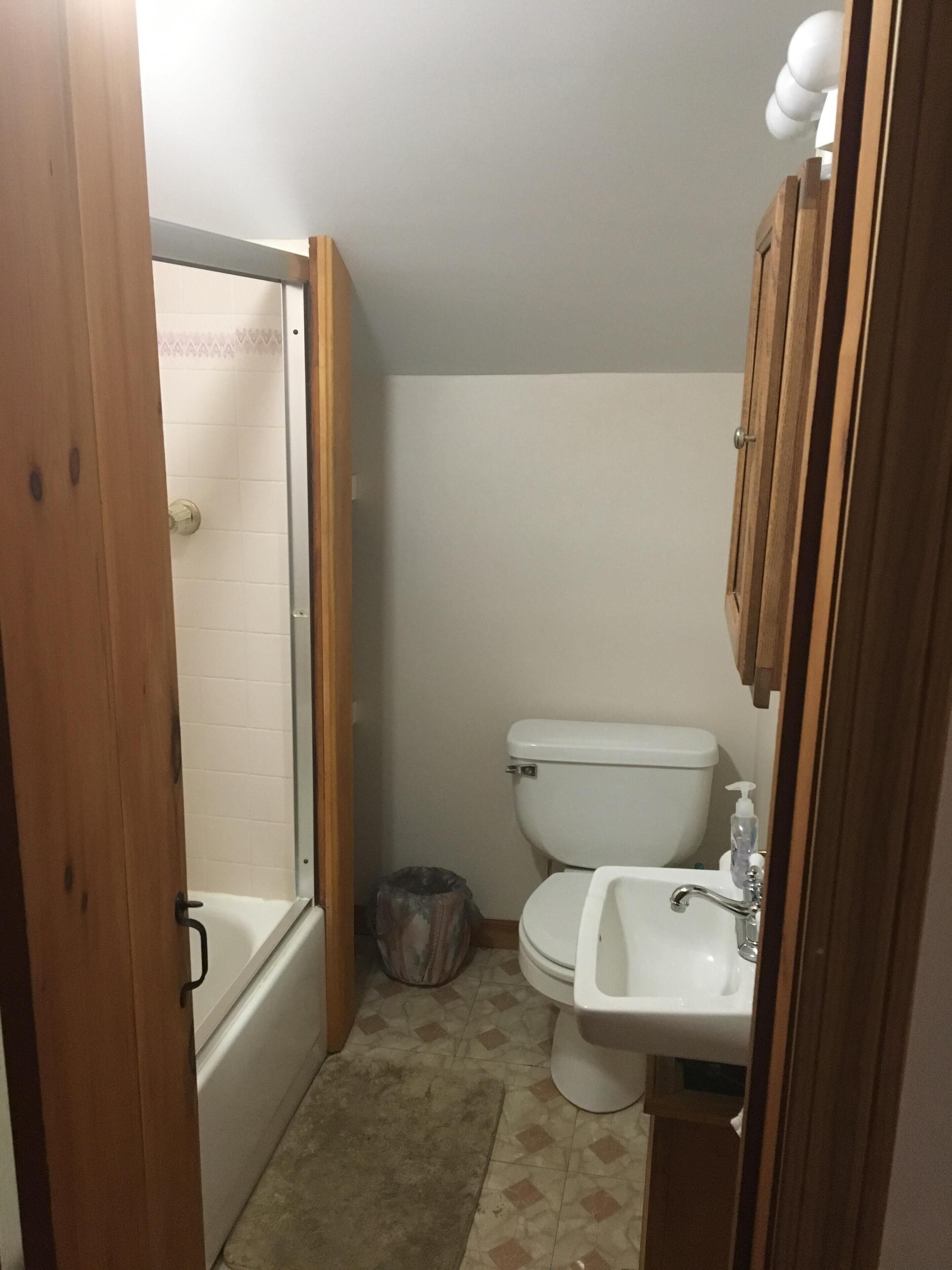 A small bathroom with a toilet, sink, and shower.