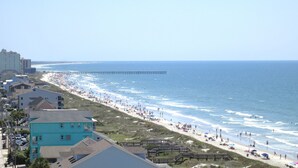 Vista costeira com uma praia, um cais e edifícios ao longo da margem.