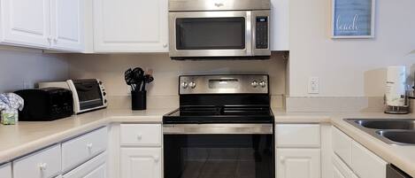 A modern kitchen with white cabinets, a stainless steel microwave, a built-in oven, and a toaster.