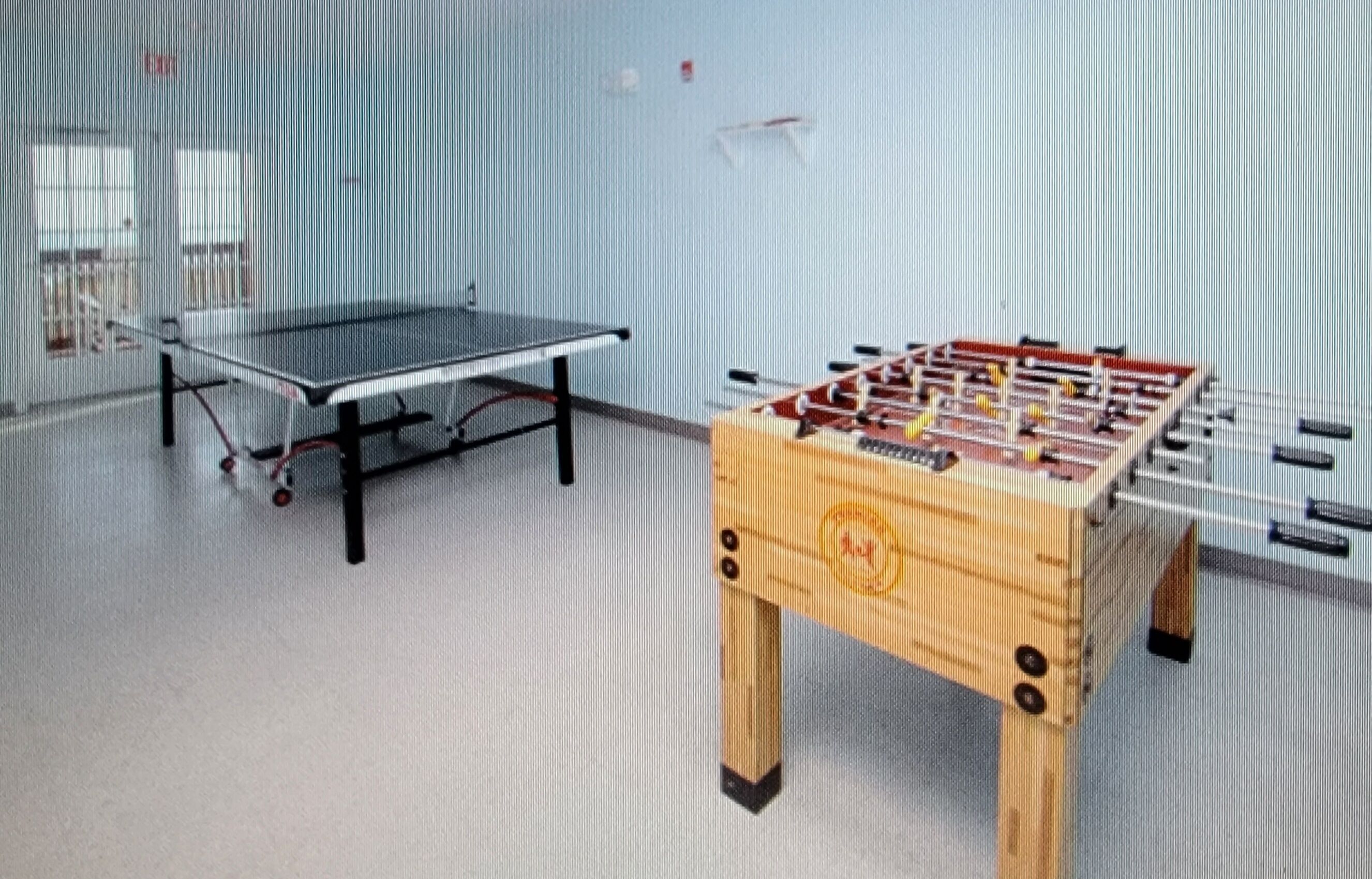 A room with a ping pong table and a foosball table.