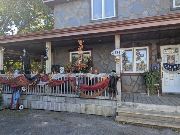 Una casa con fachada de piedra, un porche decorado con adornos de Halloween y un letrero con un número sobre la puerta.