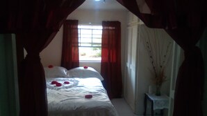 Ein Schlafzimmer mit einem Bett, Vorhängen, einem Fenster und einer Vase mit Zweigen.