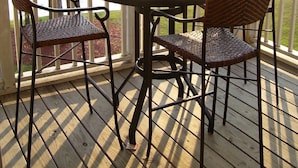 A covered outdoor patio with a round table, wicker chairs, and a view of a golf course. - Luxury Fairway Condo Overlooking Two Fairways : Near Beaches - (Leland)
