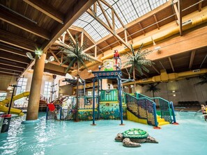 Un parc aquatique intérieur avec des toboggans, un espace de jeux et une grande piscine.