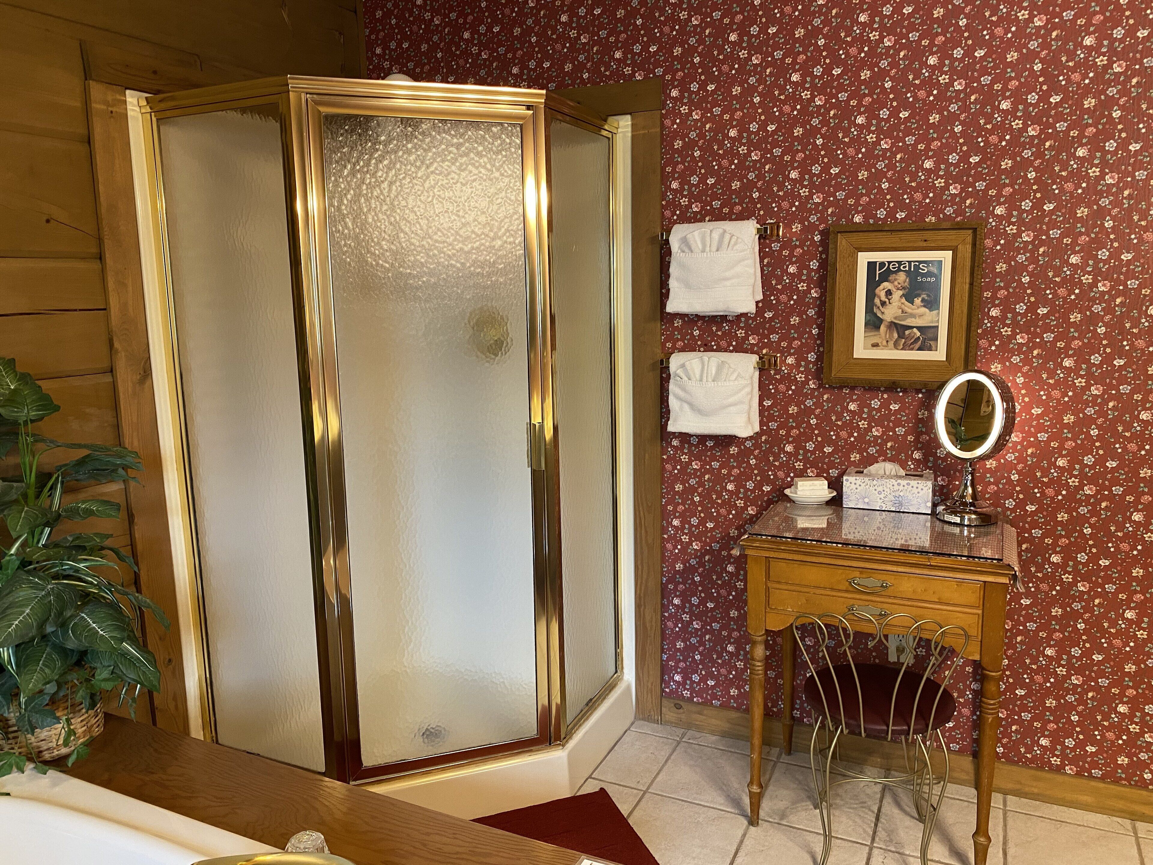 Une salle de bain avec une porte en bois, un meuble-lavabo avec un miroir et un papier peint à motifs floraux.