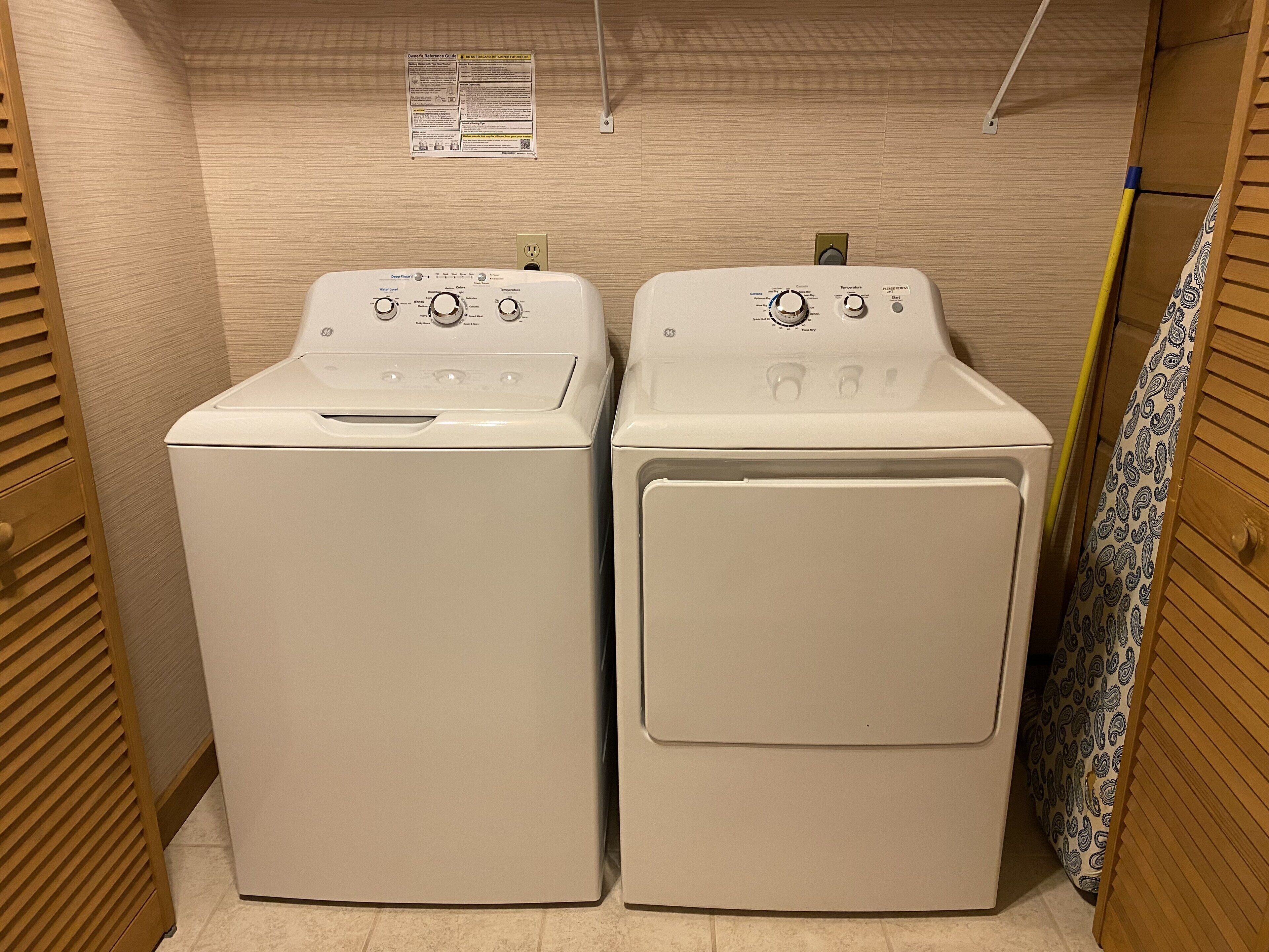 Two front-loading washing machines in a laundry room with wooden walls and a tiled floor.
