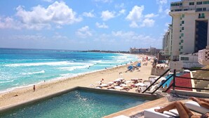 Blick vom Pool auf einen Strand mit blauem Himmel.