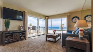 A living room with a large TV, a coffee table, a sofa, and a view of the ocean. - 5 - STAR -⭐⭐⭐⭐⭐- LUXURY OCEAN FRONT CONDO - JACUZZI - FAMILY FRIENDLY - SLEEPS 6 (San Diego)