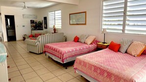 Una habitación con dos camas, un sofá, una mesa de comedor y una zona de cocina.