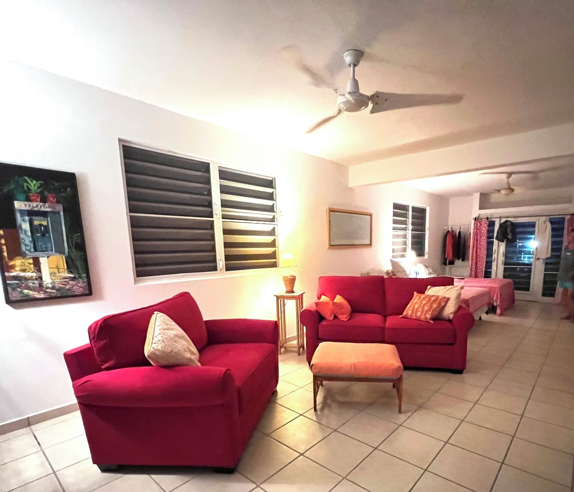 A living room with a red sofa set, a ceiling fan, and a tiled floor.