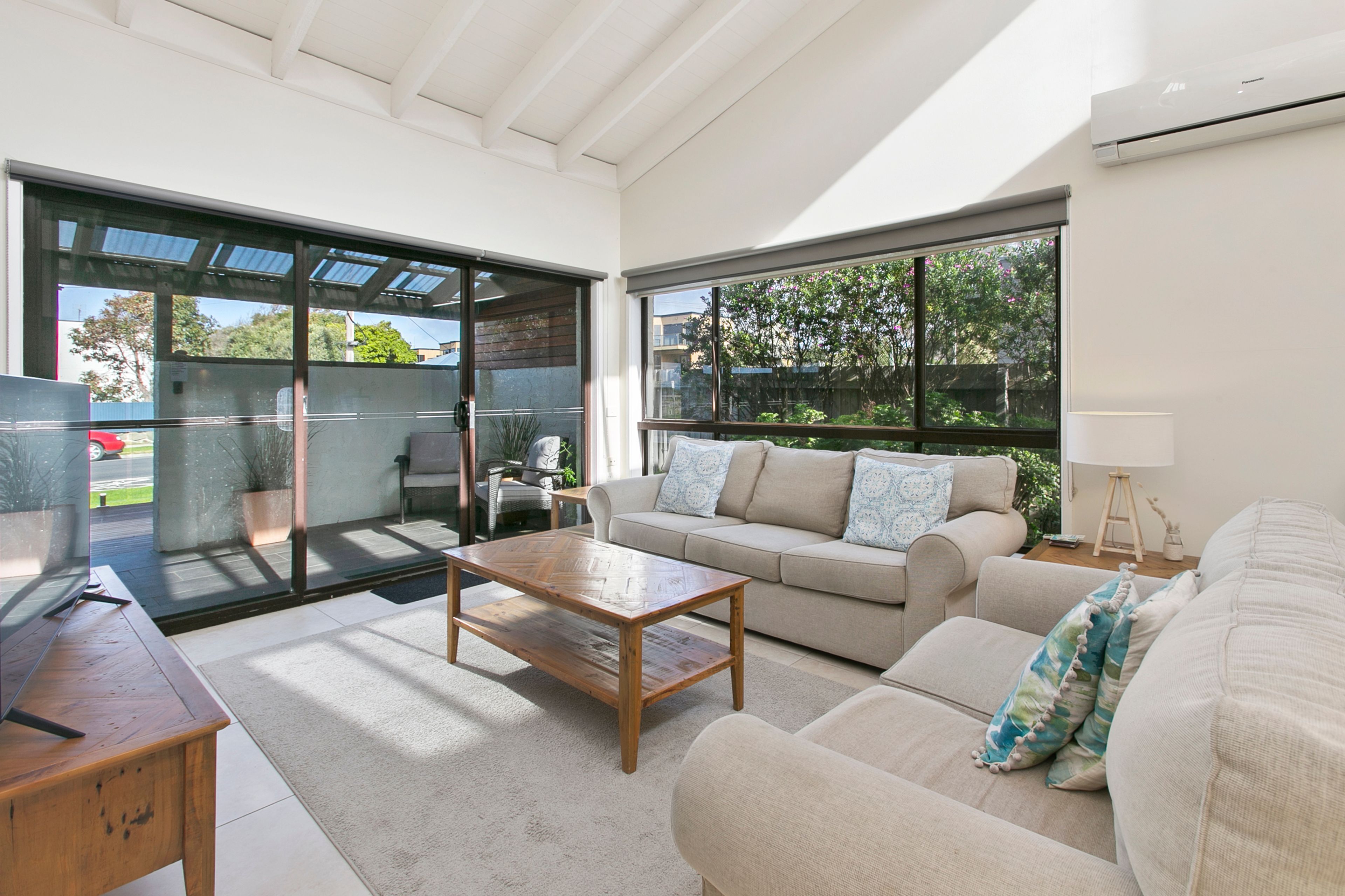 A modern living room with a sofa, coffee table, and a glass door leading to an outdoor area.