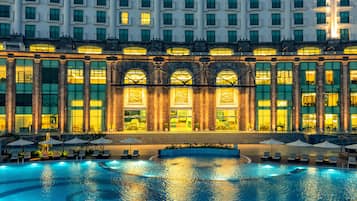 Un hotel grande con piscina, varias plantas y una entrada imponente con columnas.