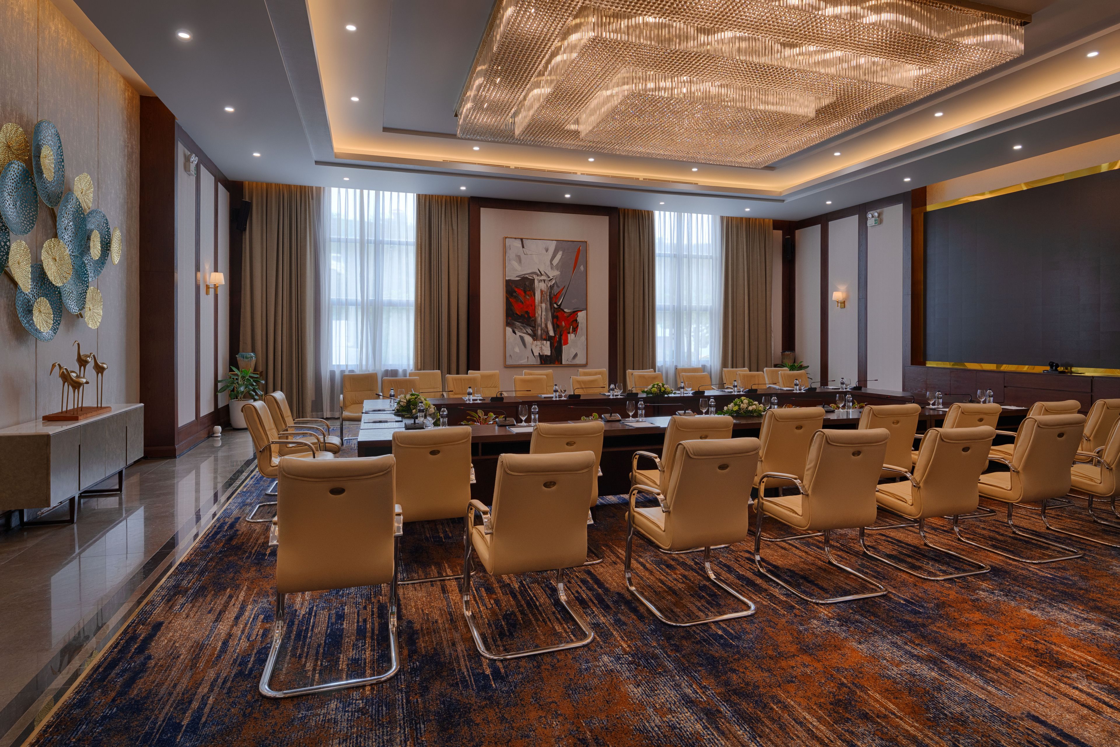 Une salle de conférence avec une longue table, de nombreuses chaises et un grand tableau abstrait accroché au mur.