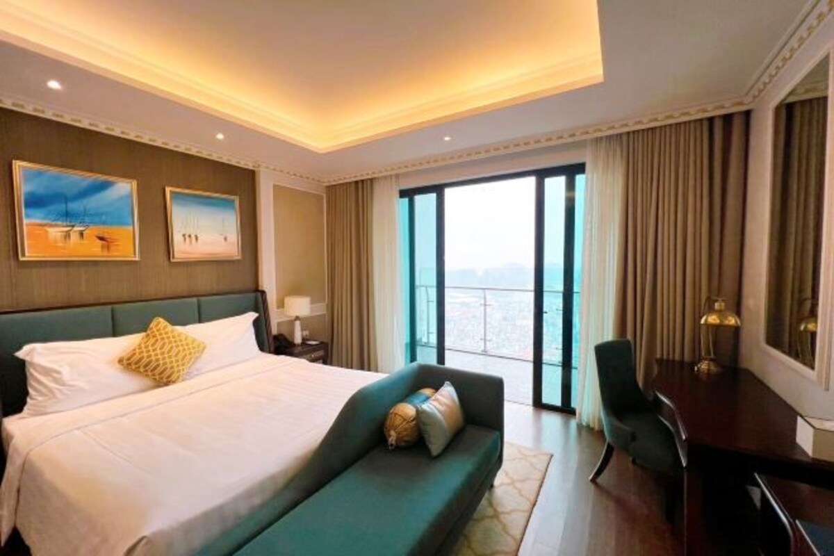A hotel room with a large bed, a desk, and a view of the city through the window.