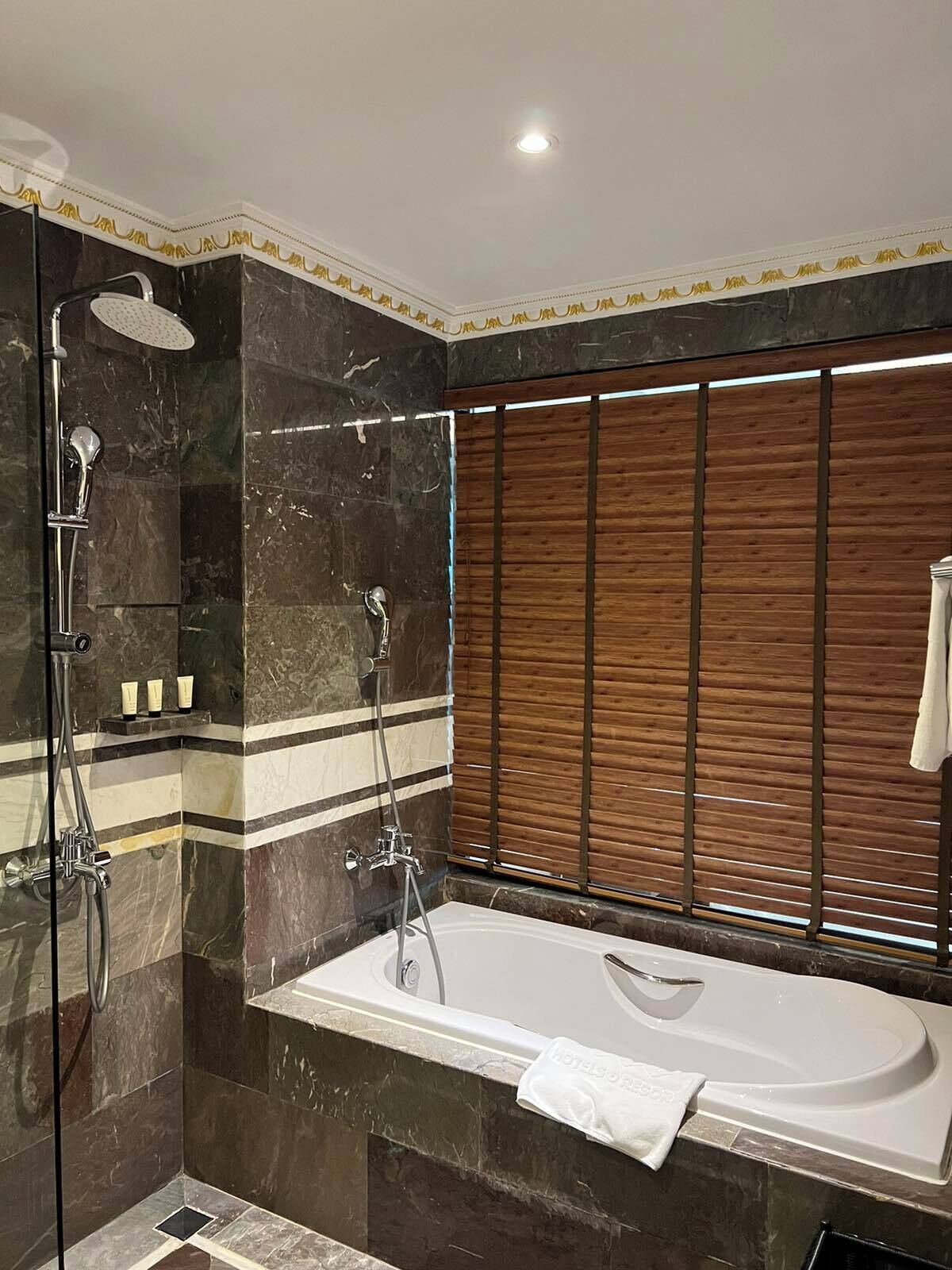 A modern bathroom with a large bathtub, a shower, and a vanity with toiletries.