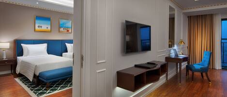 A hotel room with a large bed, a desk with a laptop, a TV, and a chair.