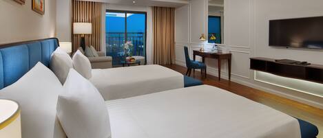 A hotel room with two beds, a desk, a chair, a TV, and a balcony with curtains.