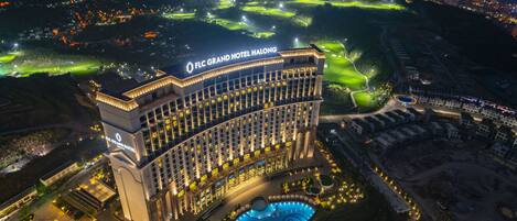 El FLC Grand Hotel Halong con una piscina grande y un campo de golf al fondo.