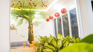 Una sala de estar moderna con un mural de un gran árbol, un sofá, una mesa de centro de madera y faroles rojos.