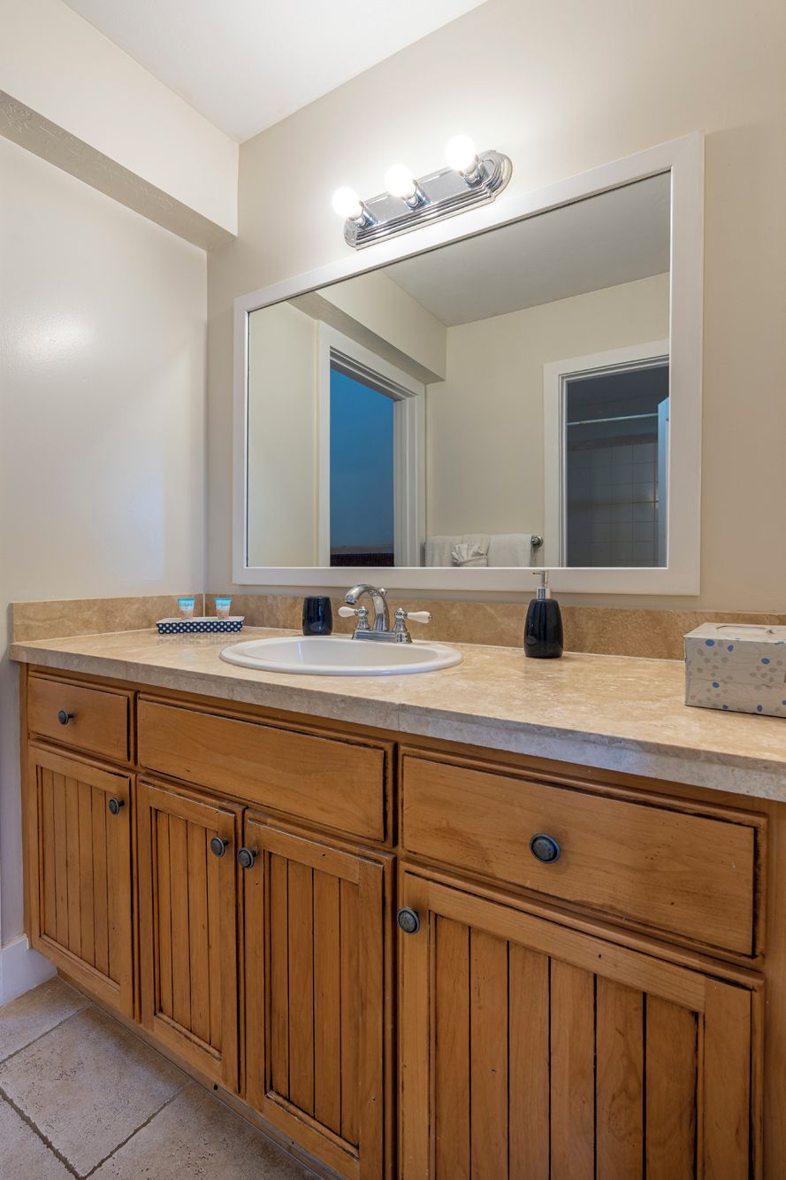 Une salle de bain avec un grand miroir, un lavabo, des meubles en bois et un porte-serviettes.