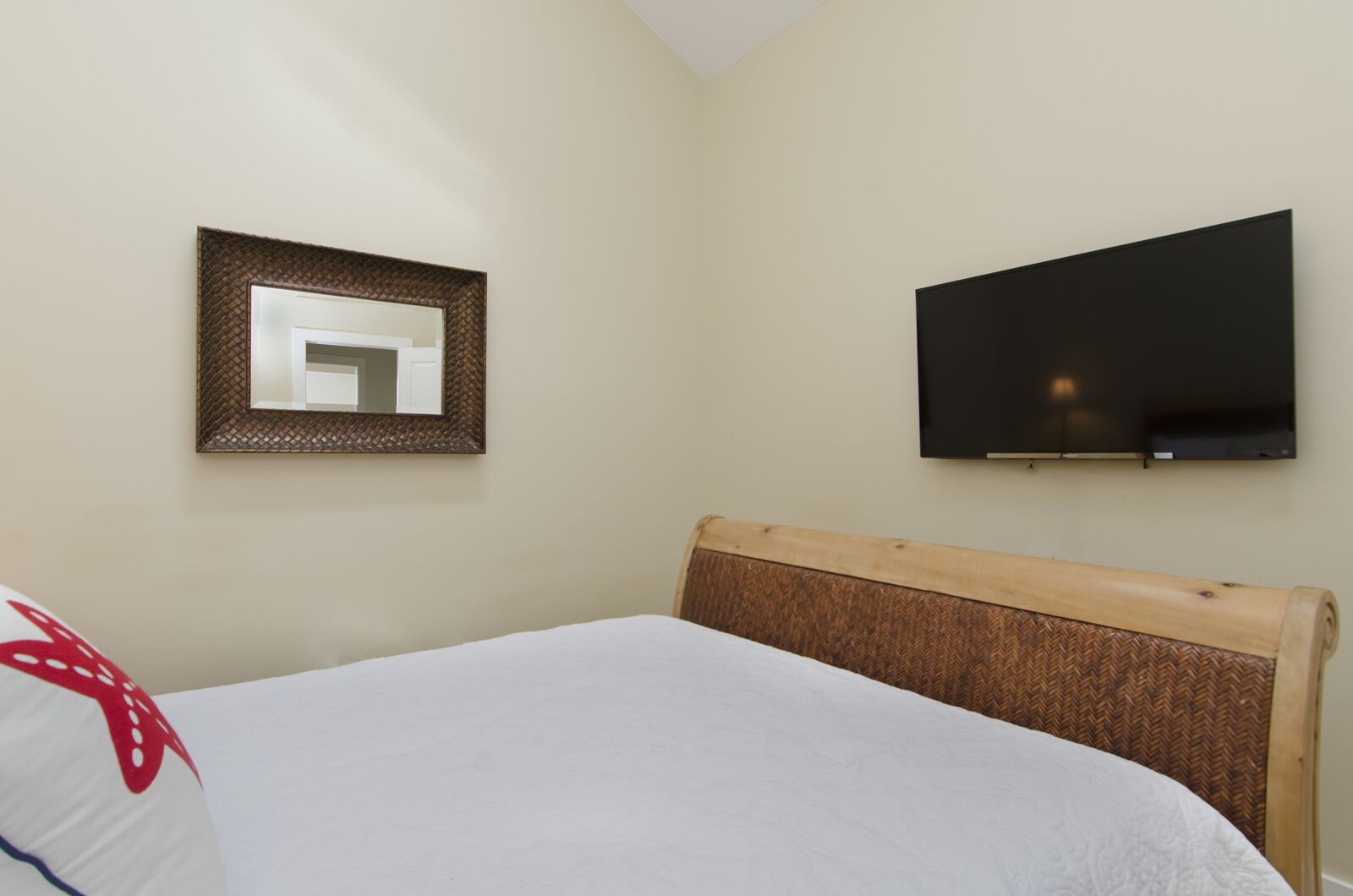 Un dormitorio con una cama, un televisor montado en la pared y un espejo.