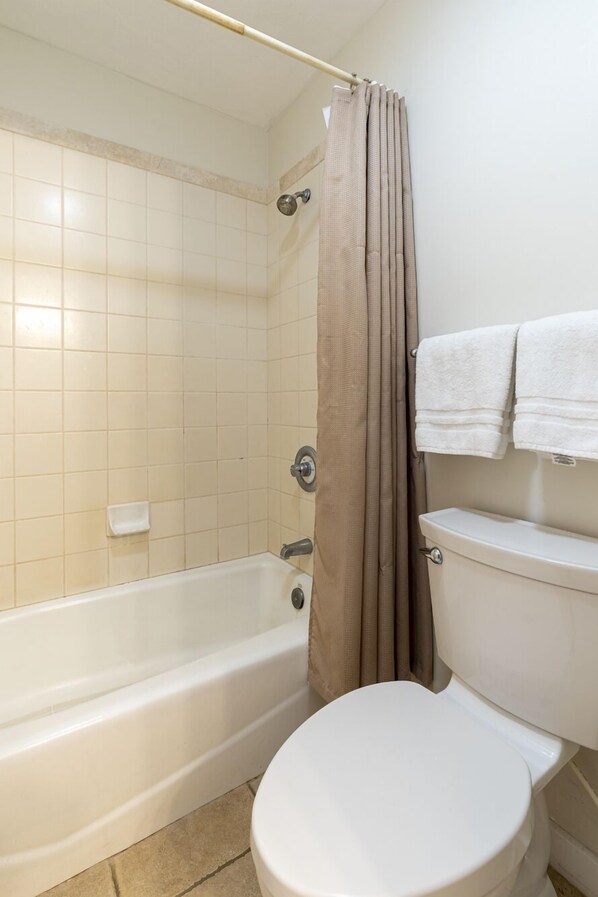 A bathroom with a bathtub, toilet, and a shower curtain. - 5 STAR!! Sleeps 8-10,3bd + loft, 3ba, A/C..5 minutes to beach,Spacious Condo. (Poipu)