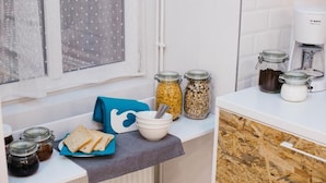 A kitchen counter with jars of condiments, a coffee maker, and a plate of bread. - Hello Hostel (Budapest)