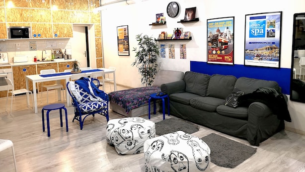 A modern hotel lobby with a kitchen area, seating, and a sofa. - Hello Hostel (Budapest)