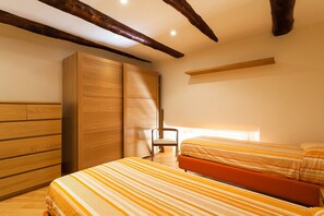 A bedroom with two beds, wooden wardrobe, and exposed wooden beams. - Casa Rossella - My Rental Homes (Sorrento)