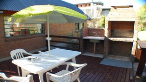 An outdoor patio with a table and chairs, a green umbrella, and a brick barbecue area with a sink. - Near Delmar (house 3) (Mar Azul)