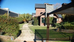 A residential property with a paved driveway leading to a house with a stone facade and a metal roof. - Near Delmar (house 3) (Mar Azul)