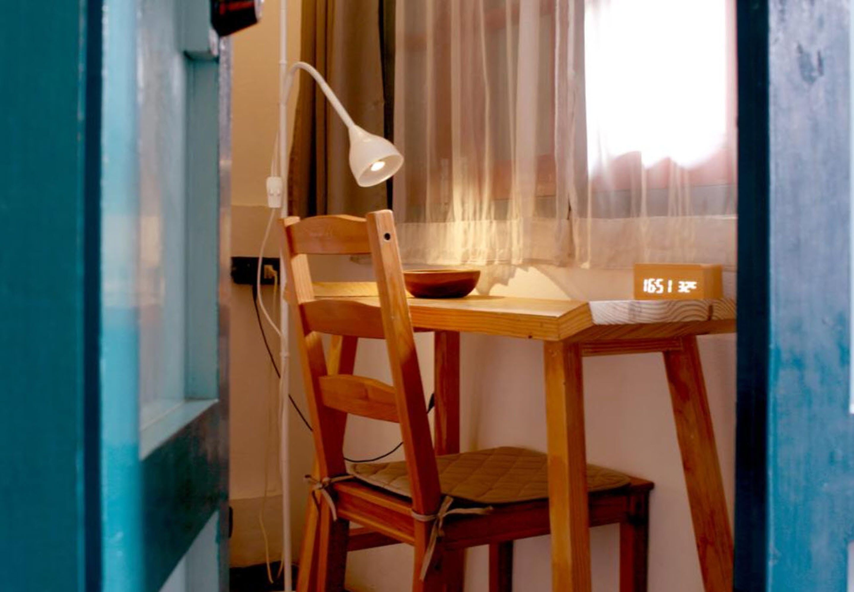 A wooden desk with a white lamp, a bowl, and a sign with numbers.
