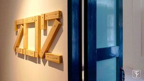 Una estructura de madera con forma de 'Z' fijada a una pared, junto a una puerta azul con un panel de vidrio.