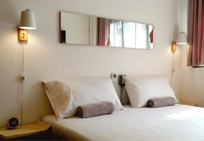 A hotel room with a bed, two bedside lamps, a bedside phone, and a clock on a nightstand. - T-Boutique Hostel (Bangkok)