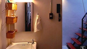 Un baño con lavamanos, espejo y cestas colgantes.