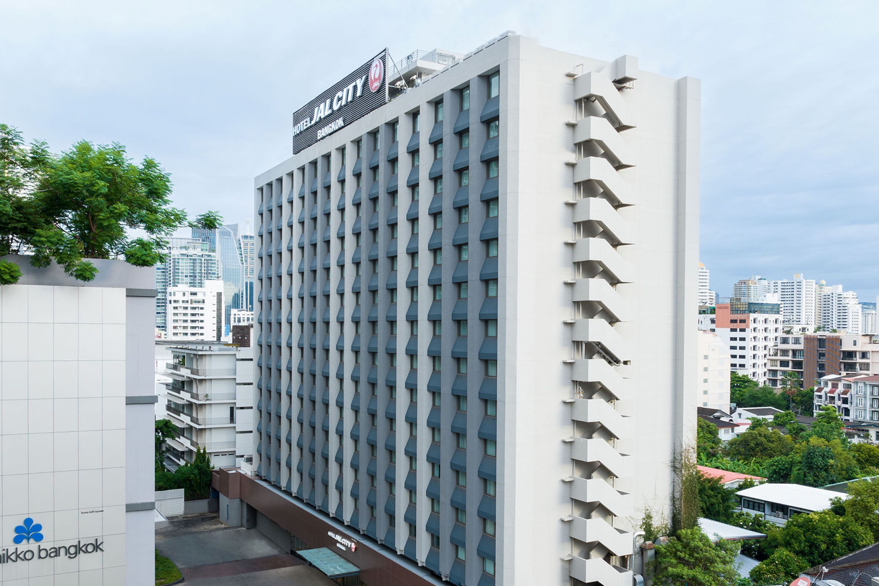 A modern hotel building with a grid of windows and a sign reading "HOTEL JACLYN BANGKOK".