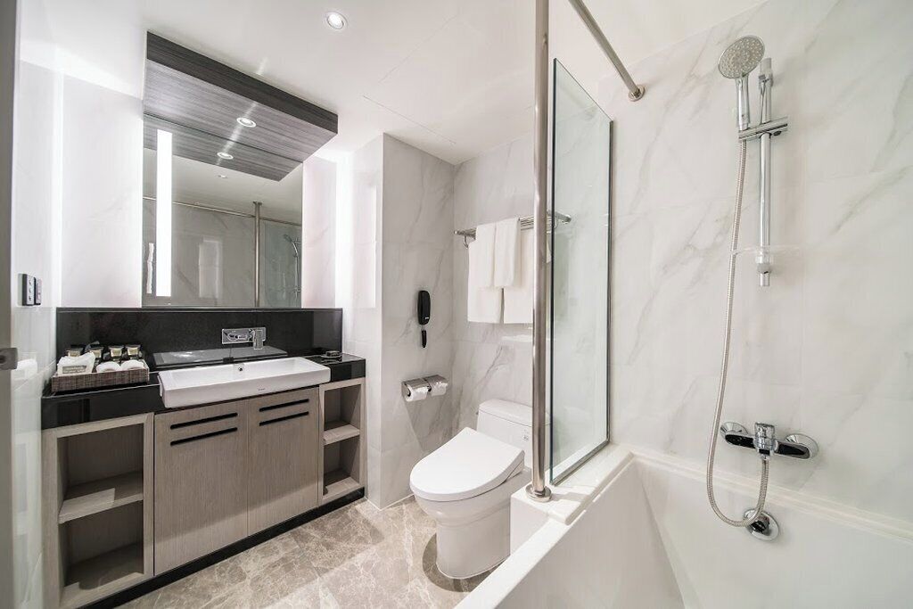 A modern bathroom with a glass-enclosed shower, a white toilet, and a vanity with a black countertop.
