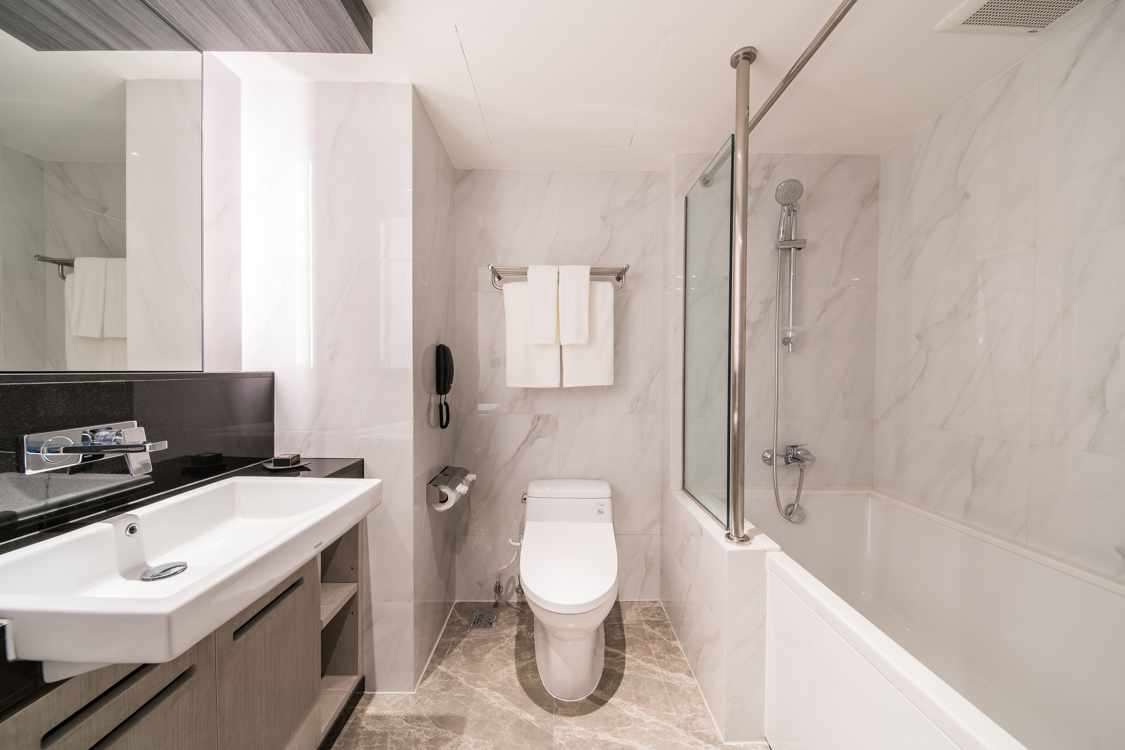 A modern bathroom with a large sink, toilet, and glass-enclosed shower.