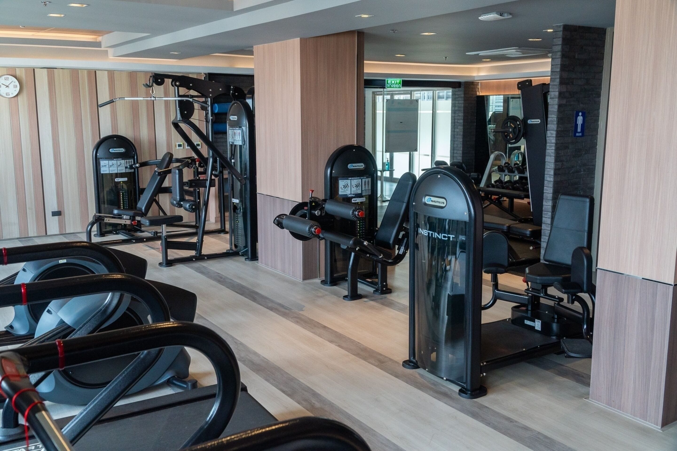 Une salle de sport équipée de tapis de course, d’appareils de musculation et d’un mur recouvert de miroirs.
