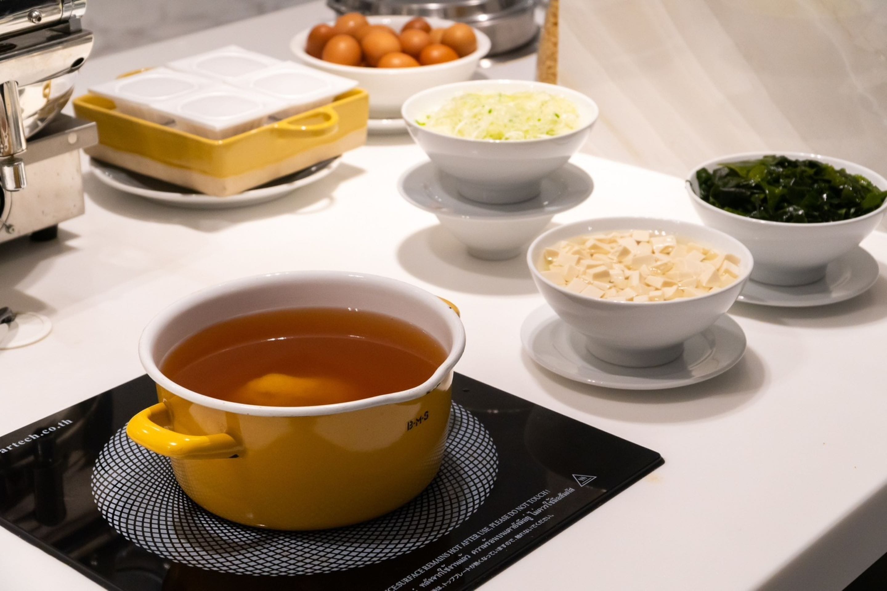 A kitchen counter with various food items and a cup of tea.