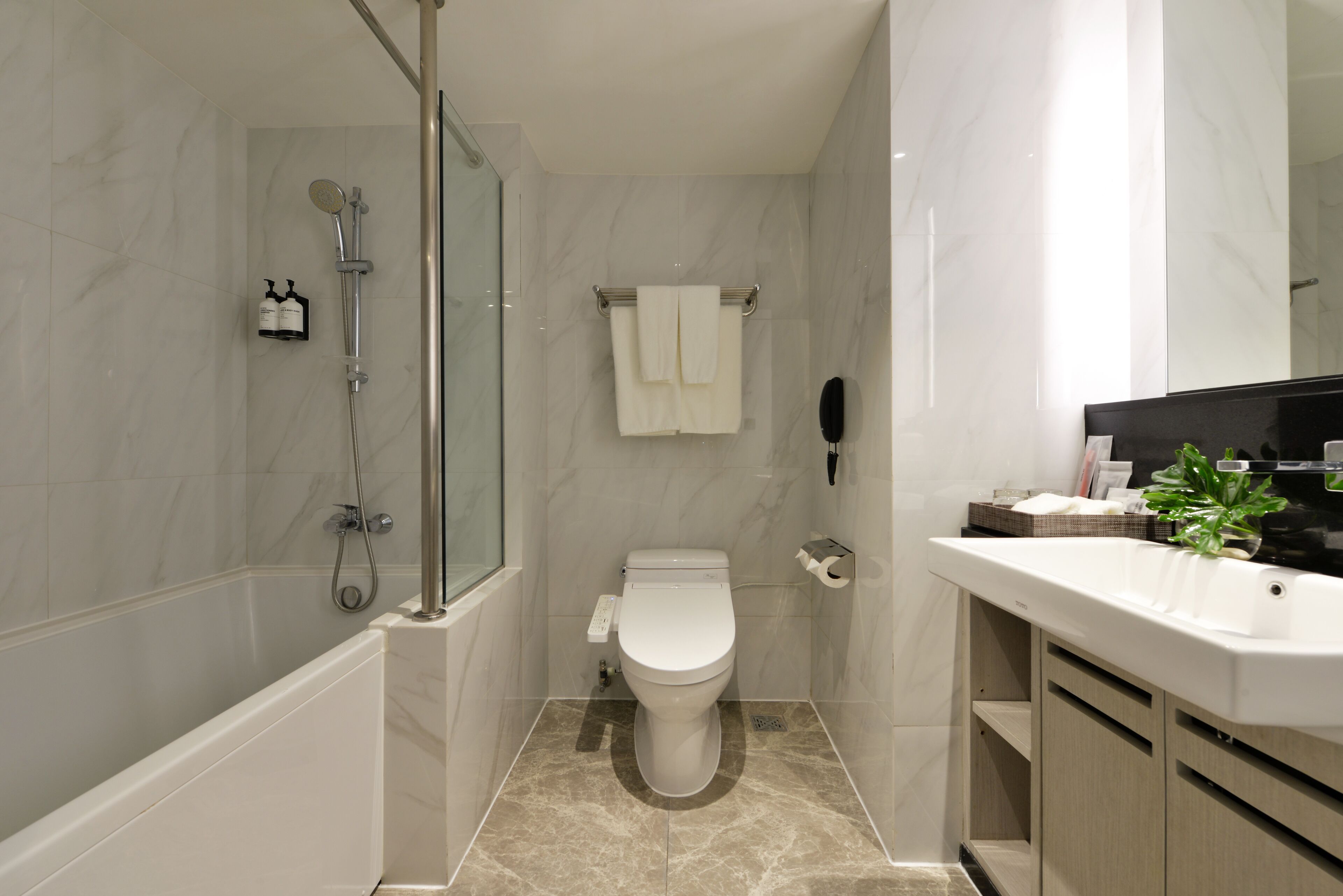 A modern bathroom with a shower, toilet, and sink.