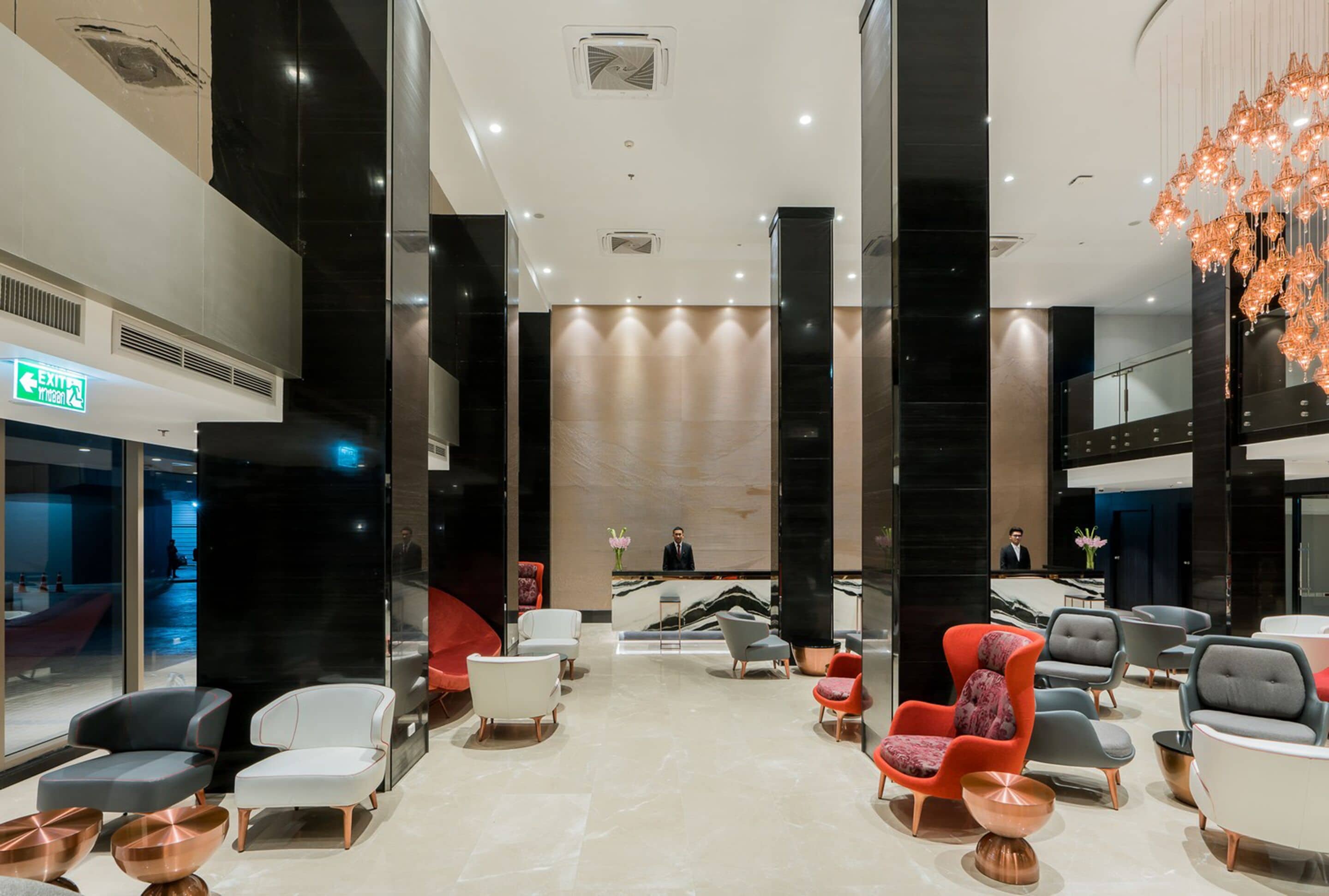 A spacious lobby with modern seating, a reception desk, and a clear exit sign.