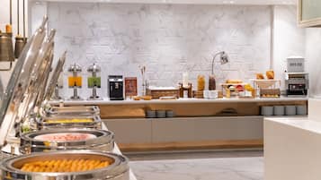 A buffet setup with various food items and a bread station.