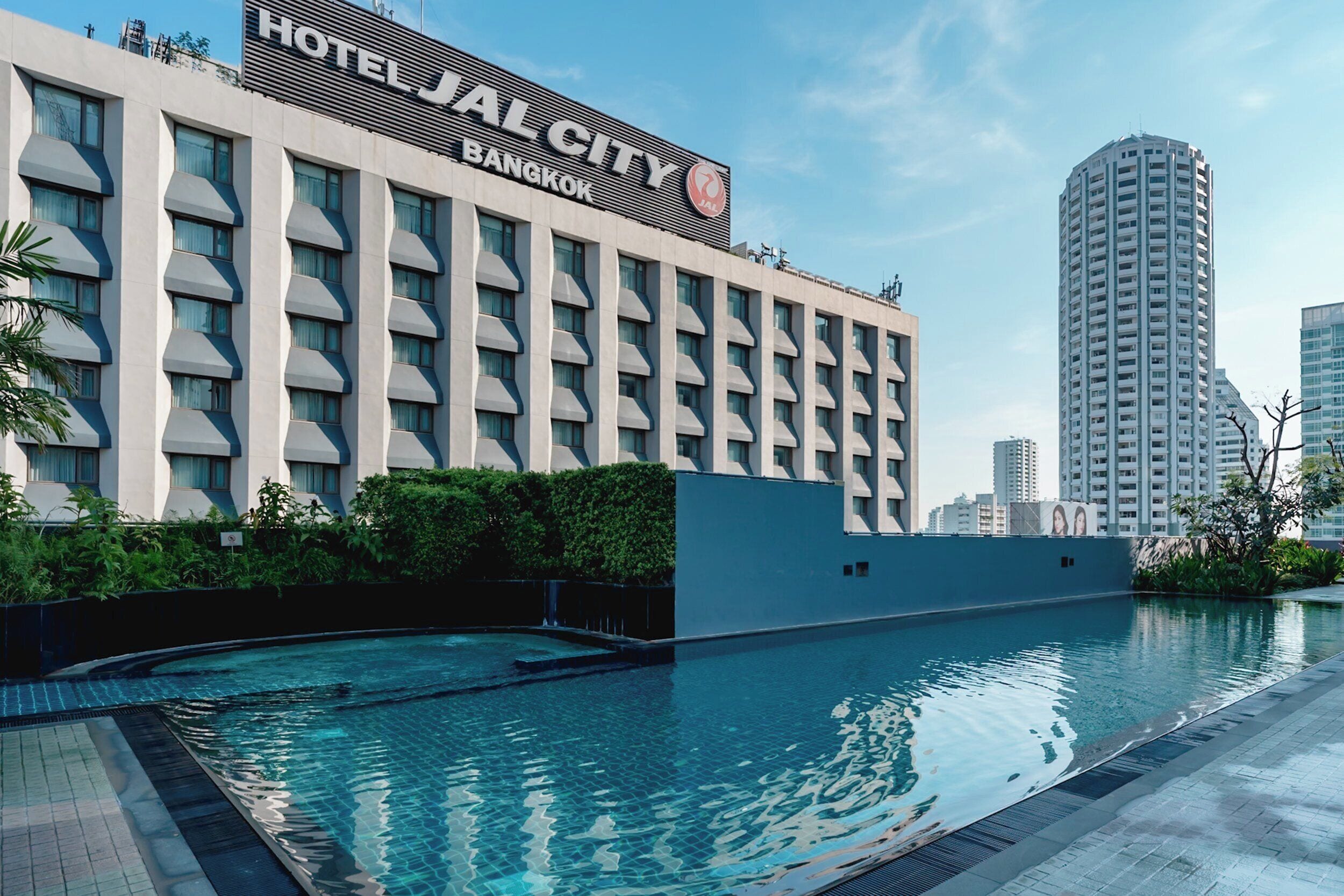 A modern hotel building with a swimming pool in front.